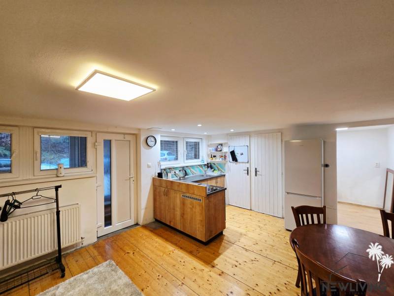A kitchen in a studio apartment with a wooden decor floor and a table.