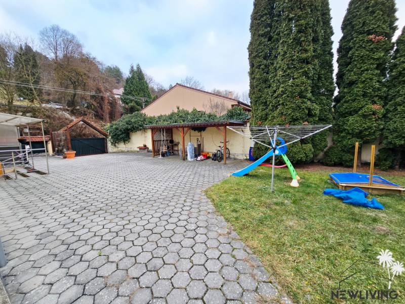 Courtyard at the Bank on Lesná Street with a playground, trees, and a paved surface.