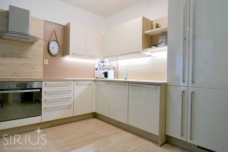 A kitchen in a 2-room apartment with white cabinets and a wood-patterned floor.