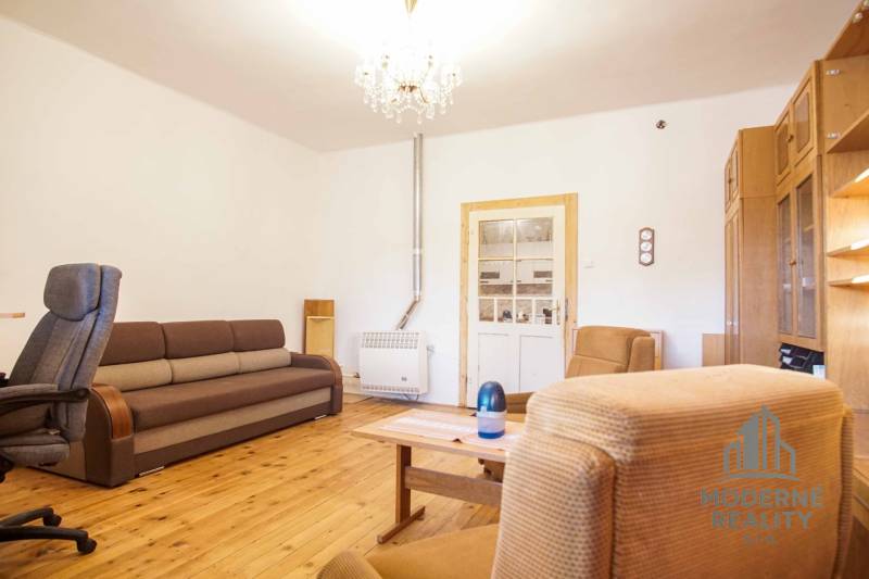 Living room in a family house with a wooden decor floor, sofa, and armchairs.