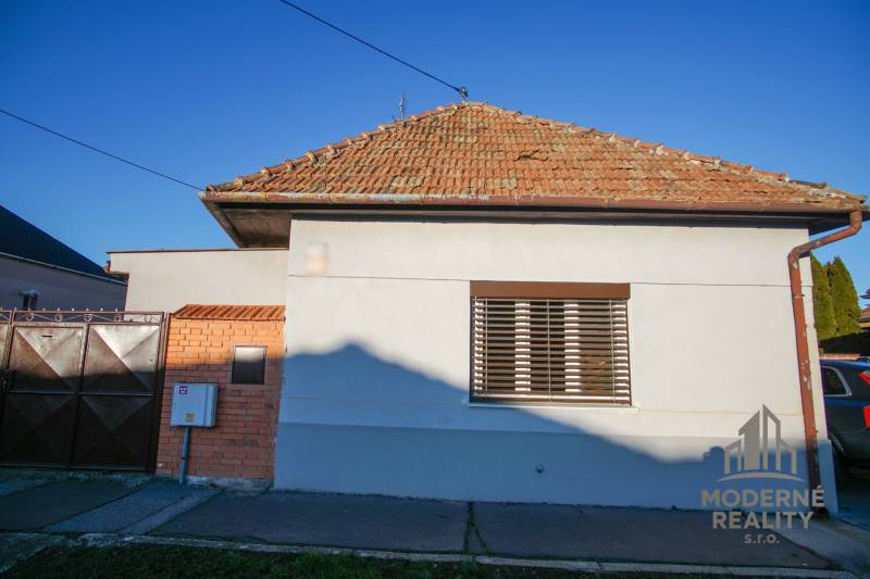A family house in Nové Zámky on Pod kopcom Street with a brick roof and a metal gate.