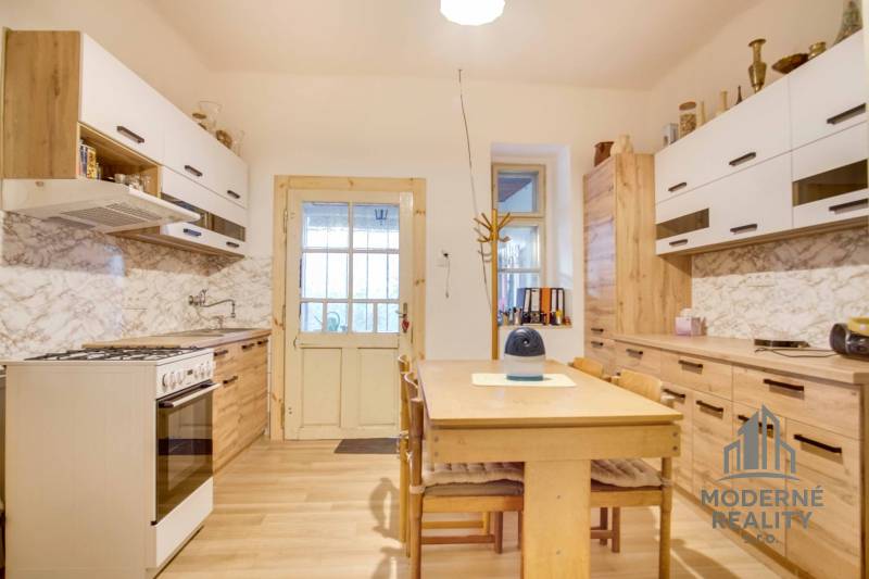 A kitchen in a family house with a wood-patterned floor and white cabinets.