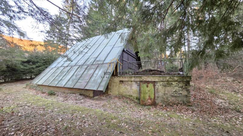 A cottage in the Krpáčovo forest on Krpáčovo street with a metal roof and a stone plinth.