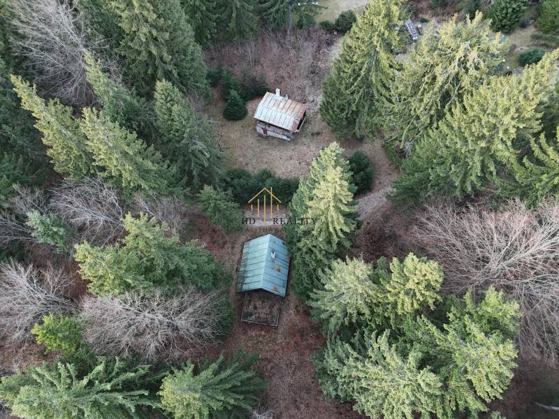 Aerial view of a cabin in the wooded area of Krpáčovo surrounded by dense trees.