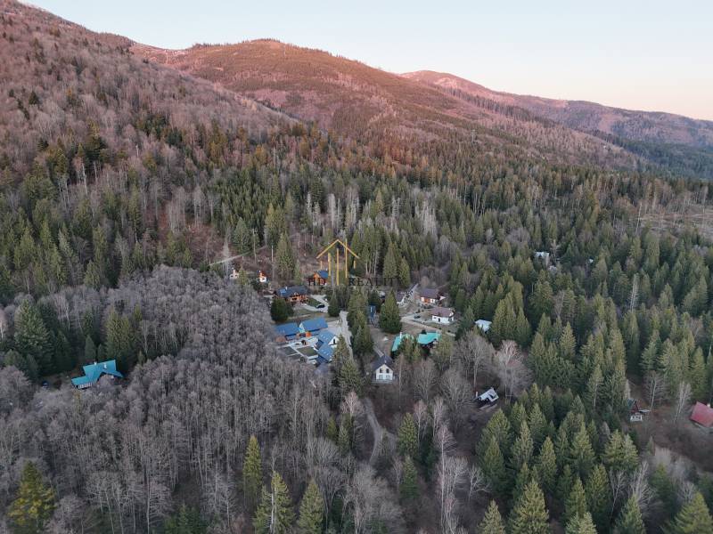 An aerial view of cabins in the forest in the Krpáčovo area surrounded by mountains and dense trees.