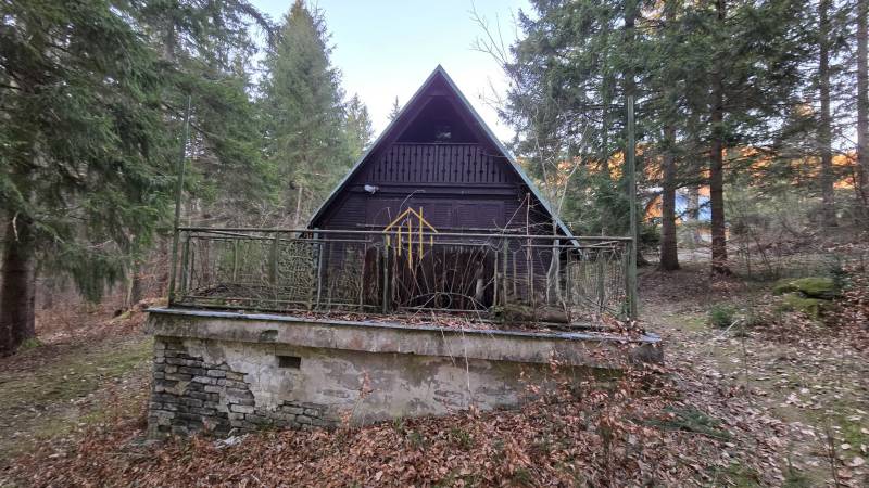 A wooden cabin surrounded by trees on Krpáčovo street in Krpáčovo at dusk.