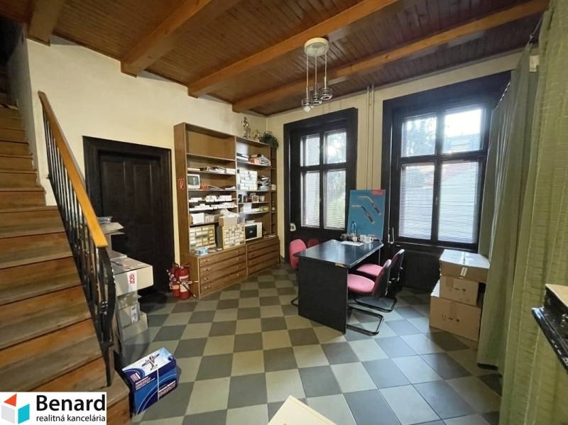 An interior with a wooden ceiling and a floor with decor, contains a table with chairs and shelves.