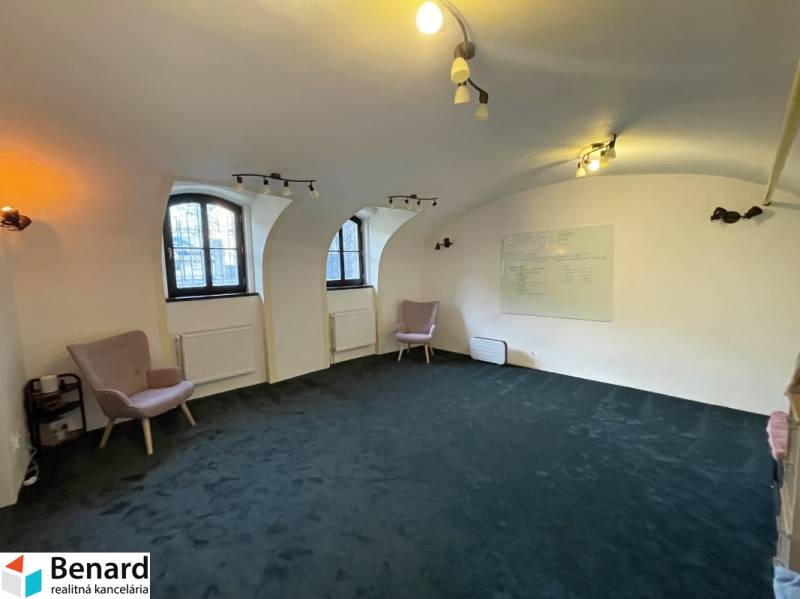The interior of a building with arched windows, green carpet, and a wall board.