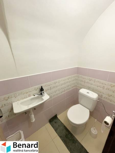 A restroom in a building with light pink tiles and a ceramic sink.