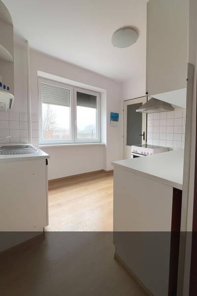 A kitchen in a family house with a window and a wooden decor floor.