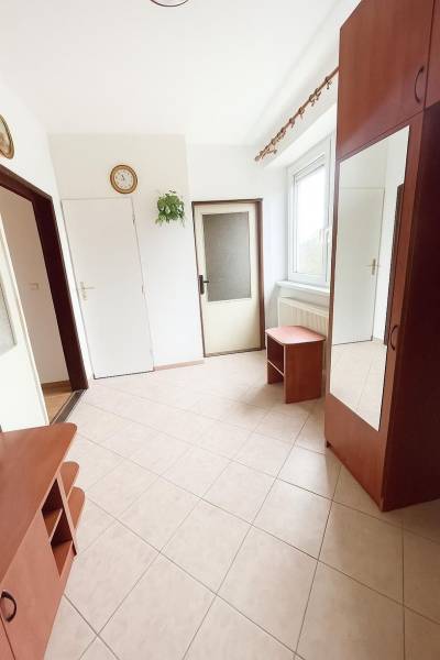 A bright hallway with tiles and wooden furniture in a family house.
