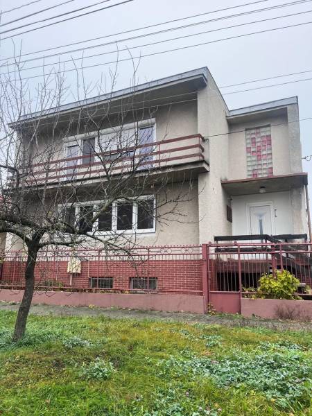 A family house in Dlhá nad Váhom with a concrete facade, a balcony, and a front garden.
