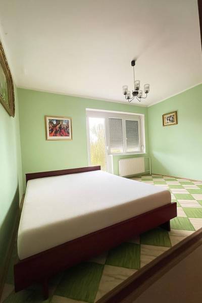 A bedroom in a family house with a bed, pastel walls, and a checkered floor.