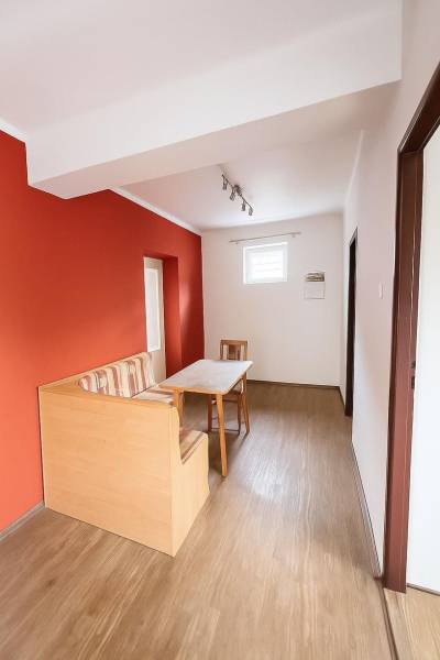 A dining room in a family house with a red wall and a wooden decor floor.