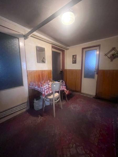 Interior of a family house with wooden paneling, a table, and a chair.