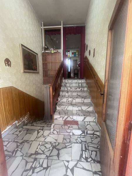 A staircase with mosaic tiles, wooden railing, and decorative wallpaper in a family house.