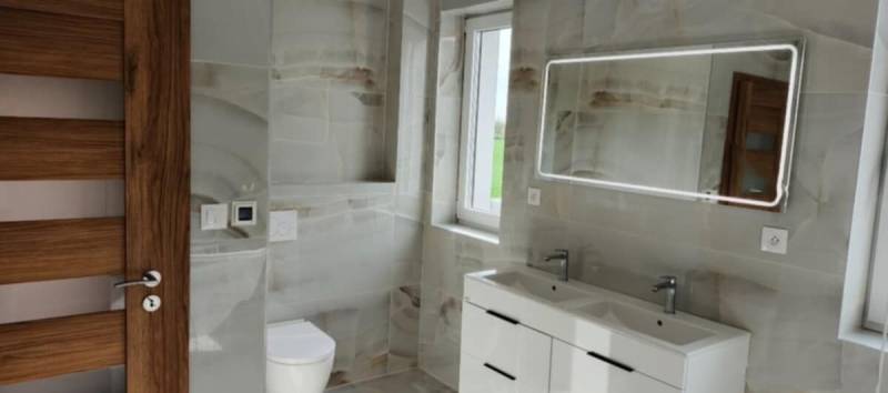 A bathroom with a modern sink, a mirror with lighting, and tiles in a 3-room apartment.
