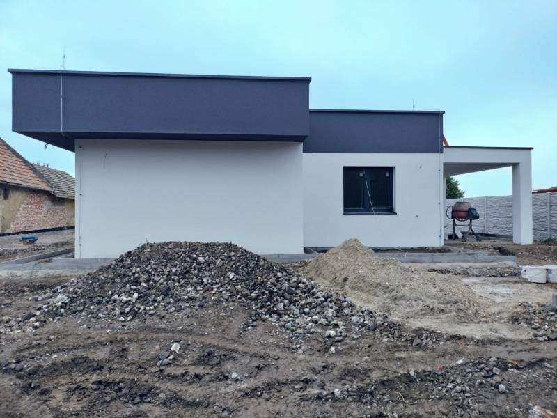 A family house in Žihárec during construction work with piles of soil and gravel.