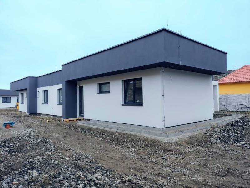 A family house in Žihárec with a white facade and a dark roof on a non-grassed plot.