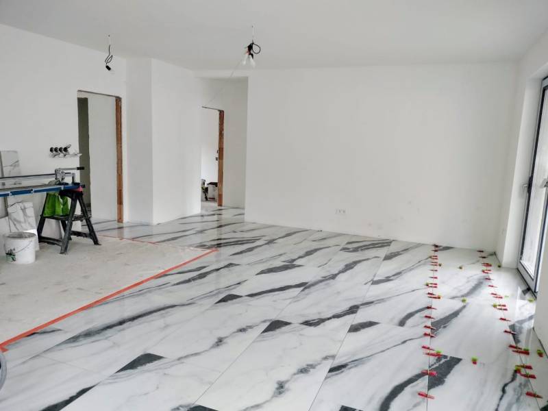Interior of a family house with a marble-patterned floor and white walls.
