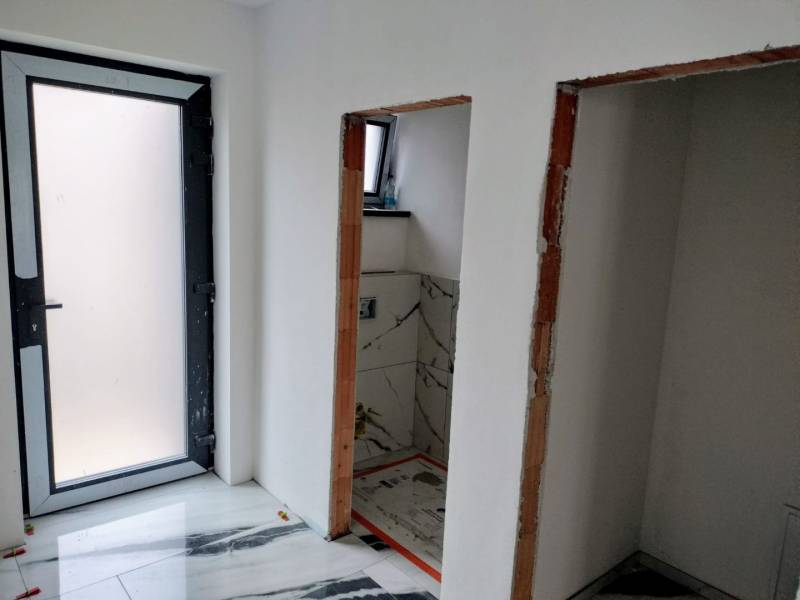 The interior of a family house with white walls and a marble-patterned floor.