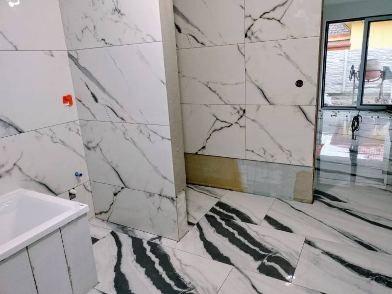A bathroom in a family house with marble walls and flooring.