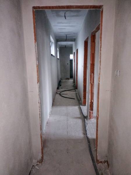 A hallway in a family house with unfinished electrical wiring and bare walls.