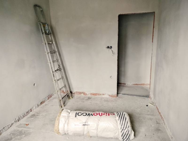 A construction room in a family house with a ladder and insulation material.