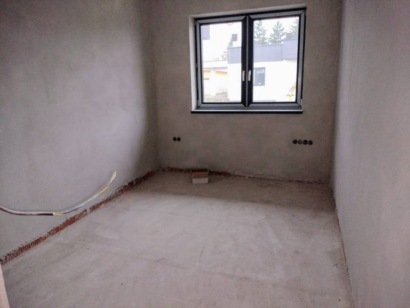 An unfinished room with new plaster and a large window in a family house.