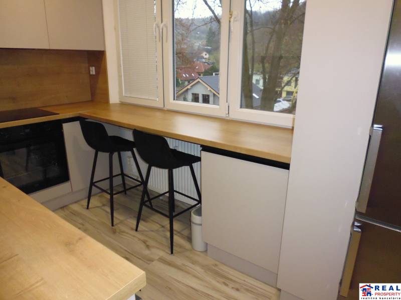 A kitchen with a table and black chairs in a 2-room apartment, floor with wooden decor.