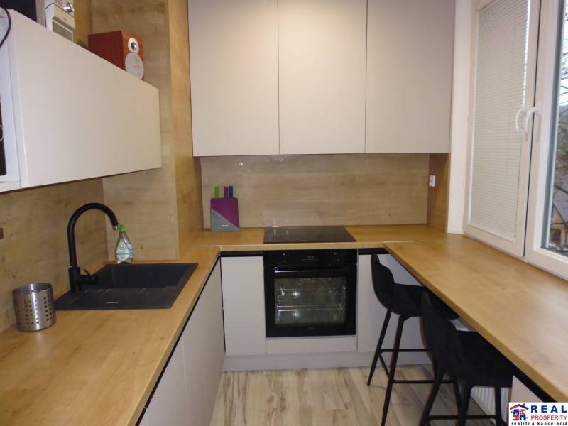 A kitchen with a wood-patterned floor in a two-room apartment, equipped with comfortable seating.