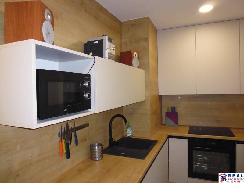 A kitchen in a 2-room apartment with wood decor, equipped with appliances and storage space.