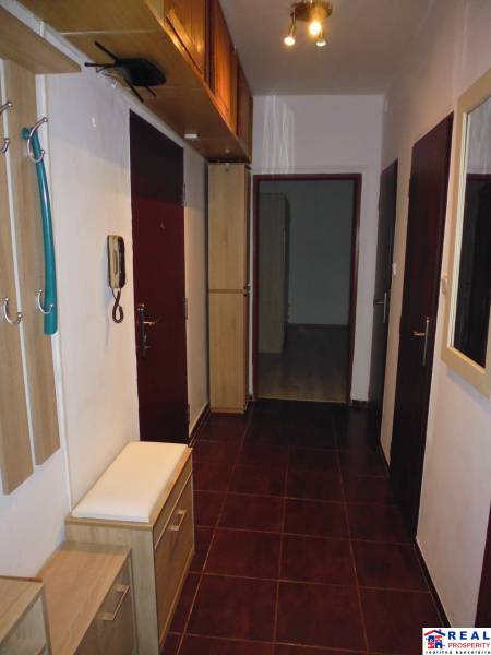 Hallway of a 2-room apartment with dark tiles and wooden decor furniture.