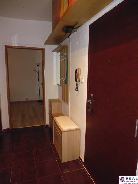 The entrance hall of a two-room apartment with a dark floor and light furniture.
