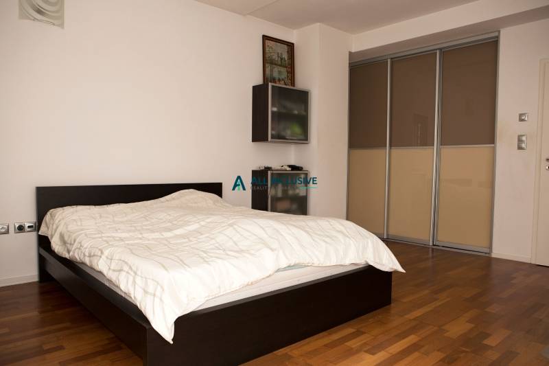 Bedroom in a family house with a bed and a wardrobe, floor with wooden decor.