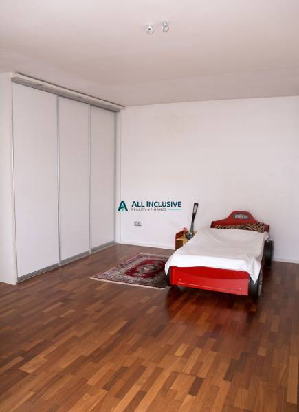 Children's room in a family house with a car-shaped bed and a wooden-patterned floor.