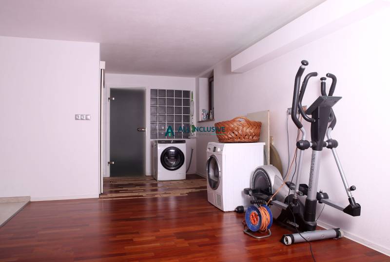 A family house with a wooden decor floor, a washing machine, a dryer, and an exercise machine.