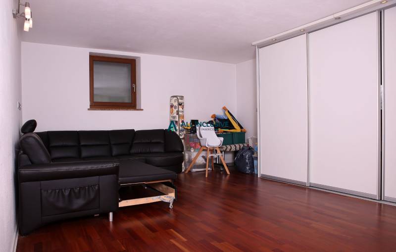 A family house with a black sofa, white cabinets, and a wooden decor floor.