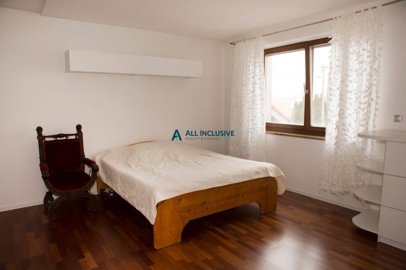 A bedroom in a family house with a bed, an armchair, and a wooden decor floor.