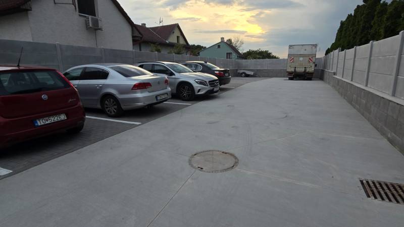Parking lot on Banka Street in Piešťany with cars and a truck at sunset.