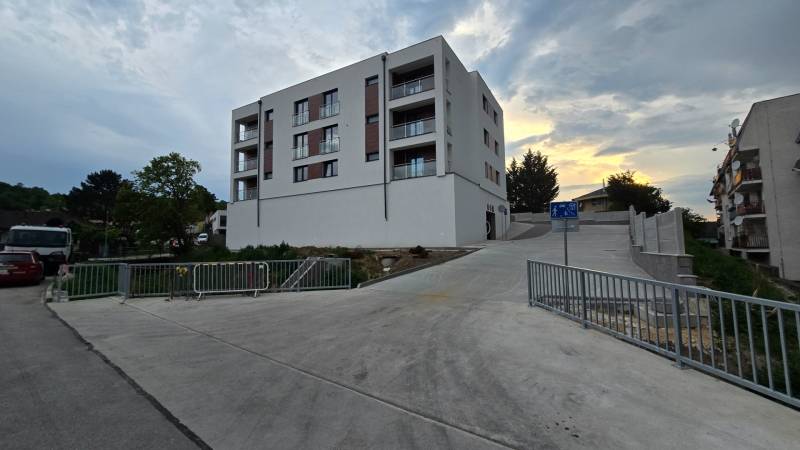 Apartment building in Piešťany on Banka street, next to the road with a sidewalk and railing.