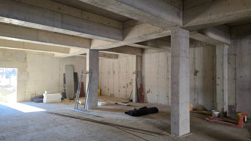 A concrete structure under construction with materials and tools in a 3-room apartment.