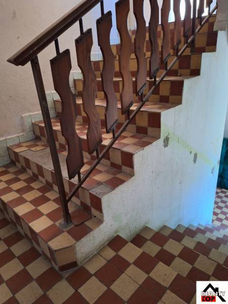 A staircase with a wooden railing in a family house with a tiled floor.