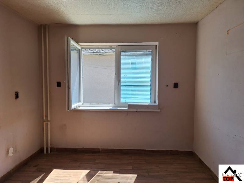 A room in a family house with an open window and a wooden decor floor.