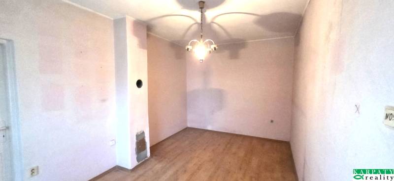 A room in a family house with a wooden decor floor and a pendant light.