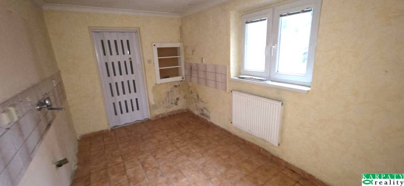 Room in a family house with light walls, a radiator, and a tiled floor.