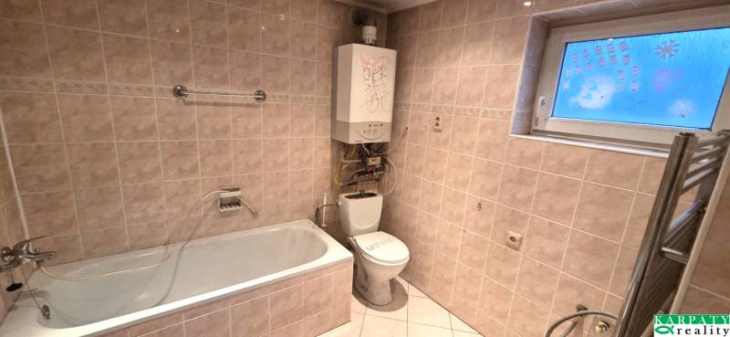 A bathroom in a family house with a bathtub, toilet, and wall heating.