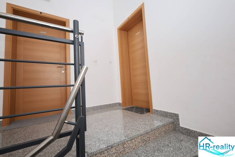 A staircase with a metal railing and wooden doors in a holiday apartment.