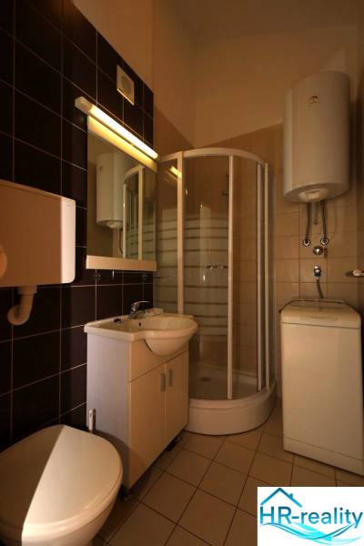 Compact bathroom with a corner shower and sink in a holiday apartment.