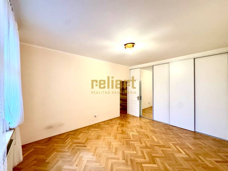 A bright room in a 4-room apartment with a wood-patterned floor and a large wardrobe.